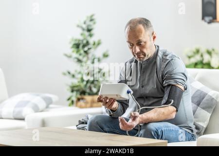 Frightened man after measuring blood pressure with a measuring device because of a bad result. Stock Photo
