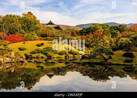 isuien gardens in nara in autumn reflections of colourful trees in the mirror lake with the borrowed scenery of mountains and nandaimon gate behind Stock Photo