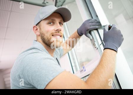 construction worker man uses screwdriver to screw handle Stock Photo
