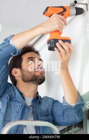cctv camera installer drilling on the wall Stock Photo