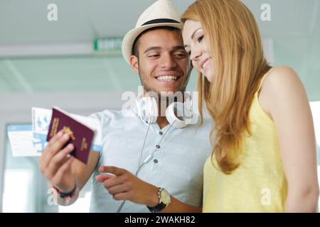 young couple at airport holding passports and boarding cards Stock Photo