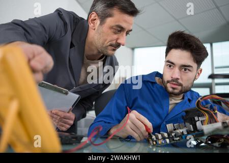 mentor guiding apprentice engineer when using a multimeter Stock Photo
