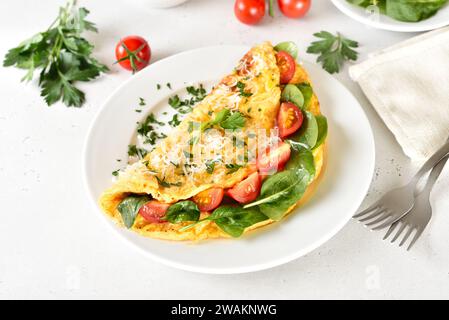 Stuffed omelette with tomatoes and spinach on plate Stock Photo