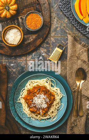 Spaghetti with homemade vegan Bolognese sauce made from red lentils and pumpkin on wooden background, turquoise earthenware, top view Stock Photo