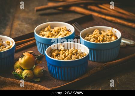 Apple crumble with cinnamon in small molds on dark wood Stock Photo