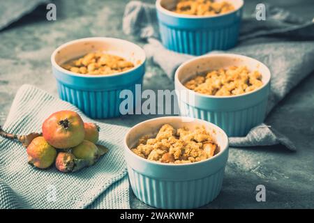Apple crumble in small blue molds on a rustic gray table Stock Photo