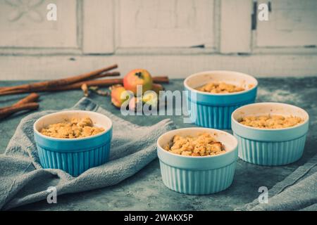 Apple crumble in small blue molds on a rustic gray table Stock Photo