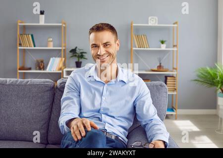 Portrait of a happy man sitting on the sofa at home, looking at the camera and smiling Stock Photo