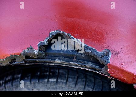 Rusty wing. Corrosion of the body of a red old car after winter ...