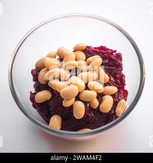 A white ceramic bowl filled with small red cranberries and light brown beans sits on a wooden table Stock Photo