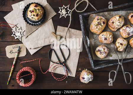 Scene for gifts in Advent with mini stollen, paper bags, and gift ribbon on dark wooden back ground, christmas concept Stock Photo