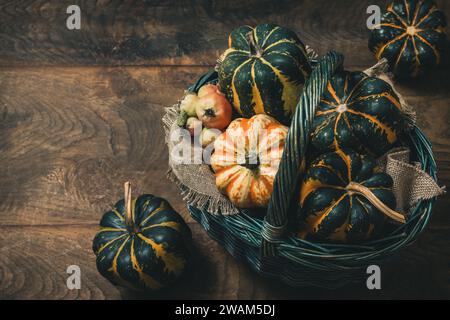 Basket with various small pumpkins on wooden background, a female hand taking one pumpkin, top view with copy space Stock Photo