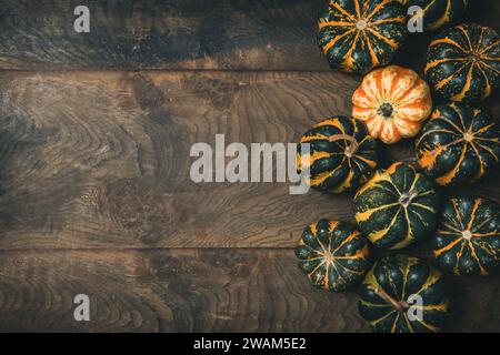 Various small pumpkins with a striped pattern on wooden background, top view with copy space Stock Photo