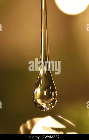Close-up of a glass drop against a blurred background with light reflections Stock Photo