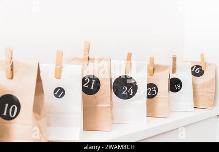 Handmade advent calendar with paper bags and stickers, standing on a white wooden board Stock Photo