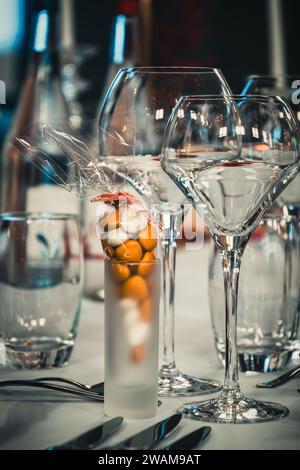 Wine glasses and candy in a shot glass as a decoration on a festive table setting, vertical Stock Photo