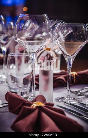 Wine glasses and candy in a shot glass as a decoration on a festive table setting in dark red colors, vertical Stock Photo