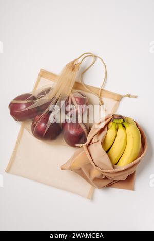 Red apples and bananas in reusable bags. Stock Photo