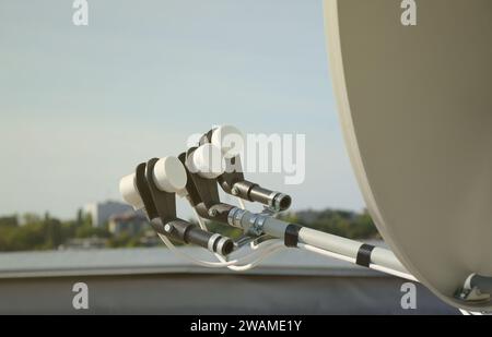 White satellite dish with three converters mounted on residental ...