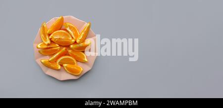 Composition with orange slices on a plate on a monochrome gray background. Playful inspiring wallpaper. Healthy food, refreshment concept Stock Photo