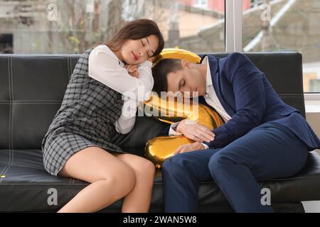 Drunk business colleagues sleeping on couch after New Year party in office Stock Photo