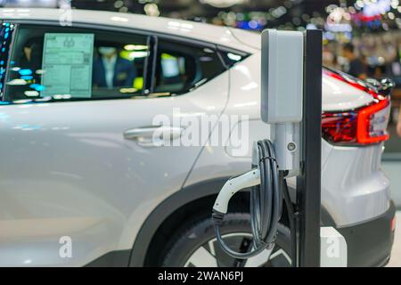 EV car rests at a charging station, power cable connected, embodying the eco-friendly future of urban transportation in action. Stock Photo