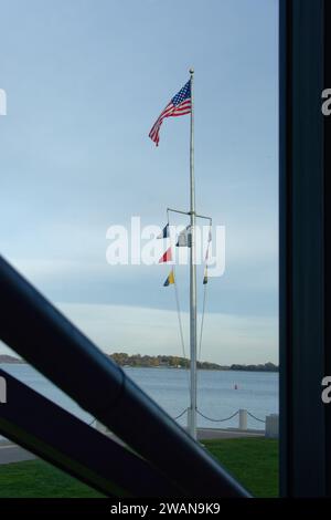 ohn F. Kennedy Presidential Library Boston - American and nautical flags hang from a pole against a darkening blue sky behind the Library. Stock Photo