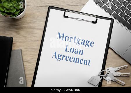 Mortgage loan agreement, house keys and laptop on wooden table, flat lay Stock Photo