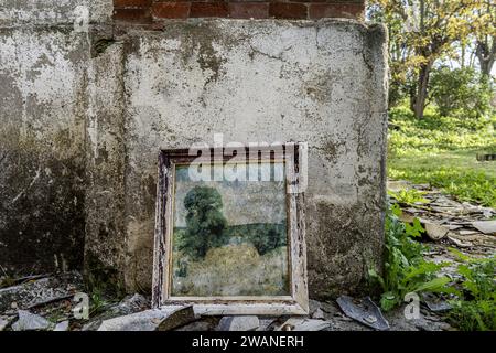 A deteriorated generic painting leaning on the outside of a ruined building Stock Photo
