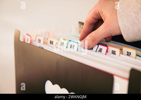 Woman Organizing Documents in a 12-Month Accordion File Organizer, Monthly Filing System with Color-Coded Tabs, Home Office, January to December Tabs Stock Photo