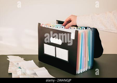 Woman Organizing Documents in a 12-Month Accordion File Organizer, Monthly Filing System with Color-Coded Tabs, Home Office, Receipts for Tax Filing Stock Photo