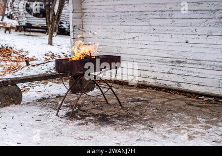 burning wood with fire in a barbecue grill in winter without people, copy space Stock Photo