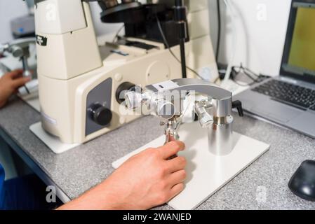 Doctor using IVF micromanipulator with Petri Dish on it for insemination of the egg in the laboratory of the in vitro fertilization. Stock Photo