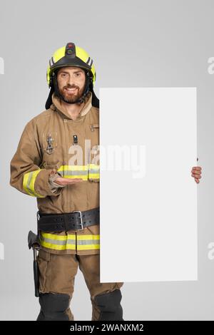 Happy firefighter holding blank banner, while looking at camera in ...