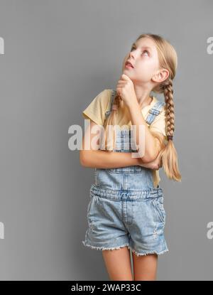 Portrait of a little girl with braided hair who is thinking and looking up Stock Photo