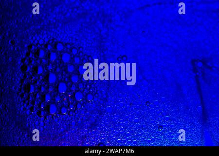 Bubbles created using soap and water mixed in cooking oil with back light through blue photography gel Stock Photo