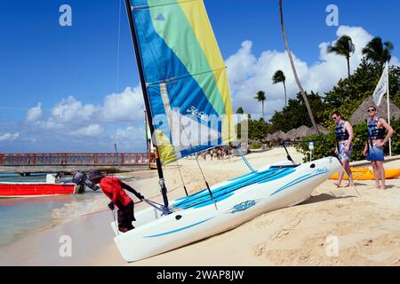 People rigging a catamaran on the beach under blue sky and palm trees, catamaran trip, Dominicus beach, Bayahibe, Dominican Republic, Hispaniola, Cari Stock Photo