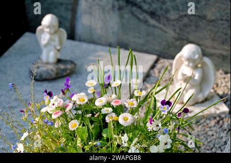 Grave decoration with little white angels and flower arrangements Stock Photo
