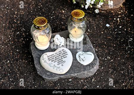 Loving decoration of a child's grave with grave lights, angels and saying hearts on a stone slab Stock Photo