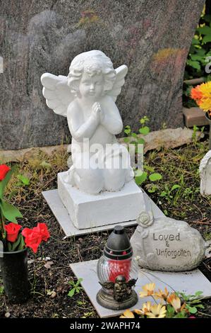 Grave decoration with small praying grave angel and stone with the inscription "Loved and unforgotten" Stock Photo