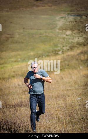 Sporty man actively descends from the mountain, feeling adrenaline and freedom of movement Stock Photo