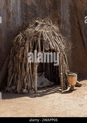 Wooden hut near the rock wall in the village of Damara tribe made from dry branches, Southern Africa. Cultural traditions of indigenous African housin Stock Photo