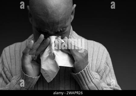 blowing nose after catching the cold and flu with grey background with people stock image stock photo Stock Photo