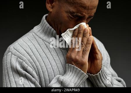 blowing nose after catching the cold and flu with grey background with people stock image stock photo Stock Photo