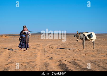 MERZOUGA, MOROCCO - JANUARY 3, 2024: a woman with her child and donkey in the Merzouga desert, Morocco Stock Photo