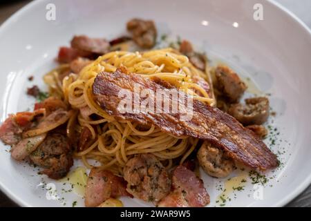 Spaghetti Aglio e Olio, garlic and olive oil, served with sausage and bacon Stock Photo
