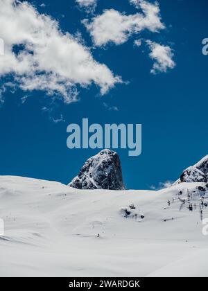 An incredible, panoramic view of a snow-capped mountain range, illuminated by vibrant blue skies and illuminated by fluffy white clouds Stock Photo