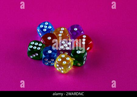 Coloured plastic gaming dice on a pink table top Stock Photo