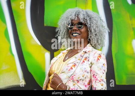 Self-confident, stylish afro-american lady with hoary afro hair and sunglasses smiling with green graffiti in the background. Concept: pro-aging, self Stock Photo