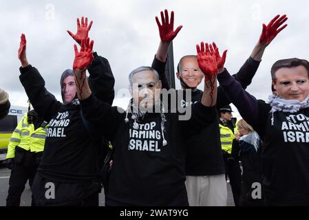 London, UK. 6 January, 2024. Activist with hands covered in fake blood wear masks depicting Israeli Prime Minister Benjamin Netanyahu, UK PM Rishi Sunak and Foreign Secretary David Cameron, and US President Joe Biden as the Free Palestine Coalition stage a protest blocking Westminster Bridge demanding an immediate ceasefire, an end to UK arms sales to Israel and an end to Israeli occupation of Palestine. Credit: Ron Fassbender/Alamy Live News Stock Photo
